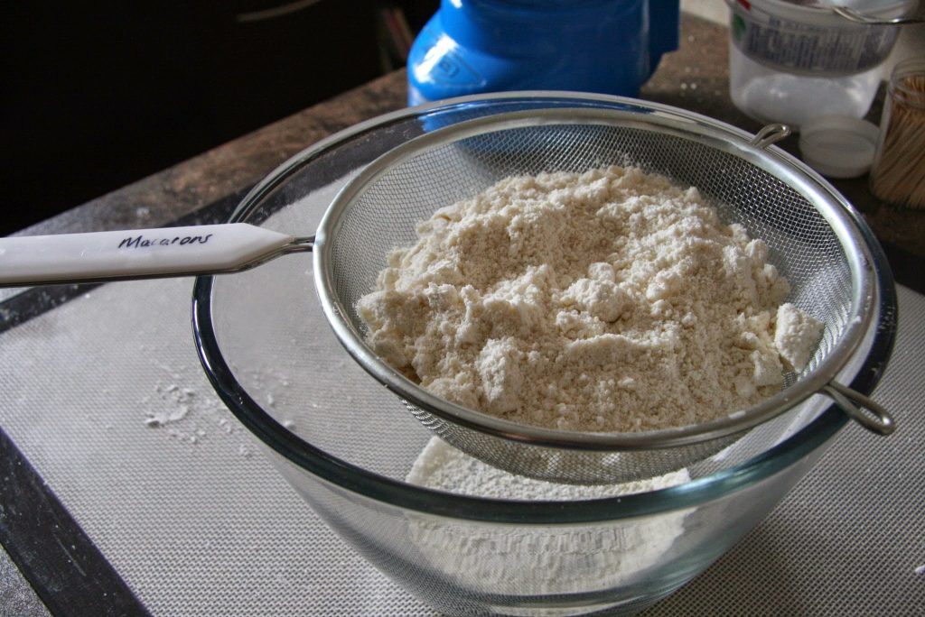 Sifting processed almond meal and powdered sugar. 