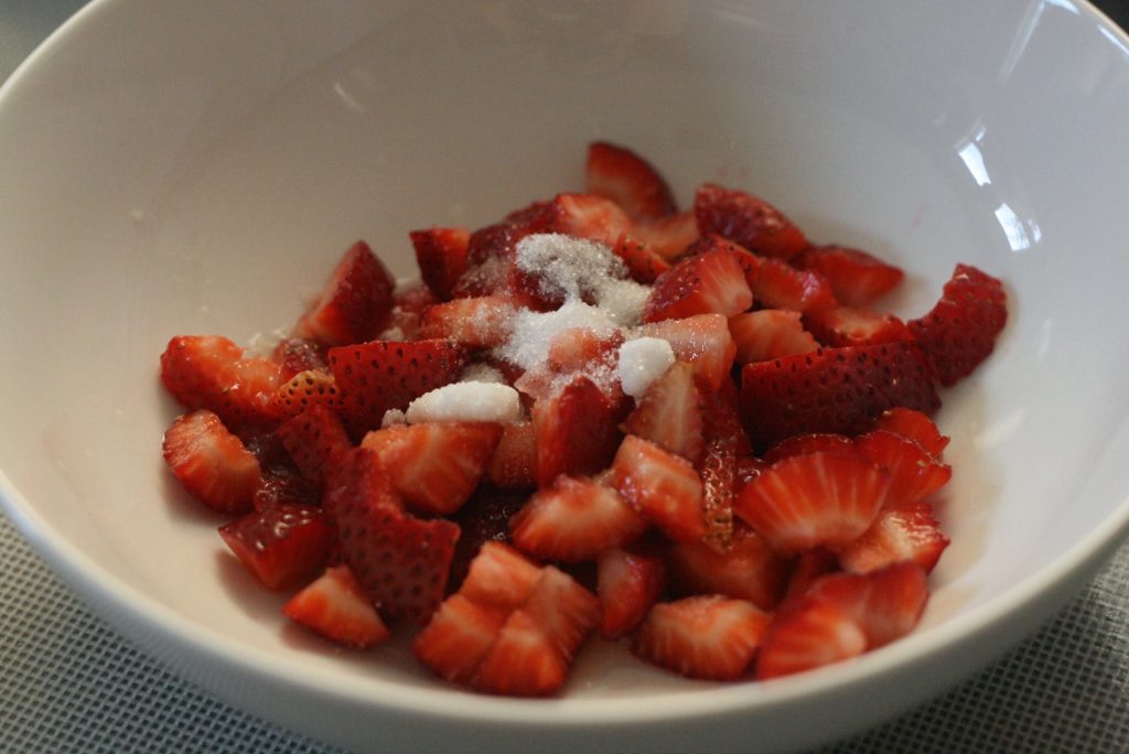 Strawberries macerated with sugar and lemon juice in a bowl. 