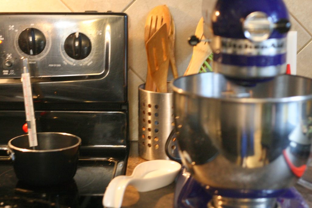 Water-sugar solution in heavy bottom pot on stove & egg whites whisking in mixture. 