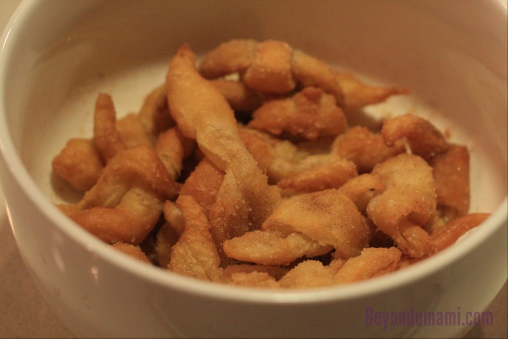 Bowl of left-over puff pastry scraps deep-fried and sprinkled with sugar. Bowl of left-over puff pastry scraps deep-fried and sprinkled with sugar.