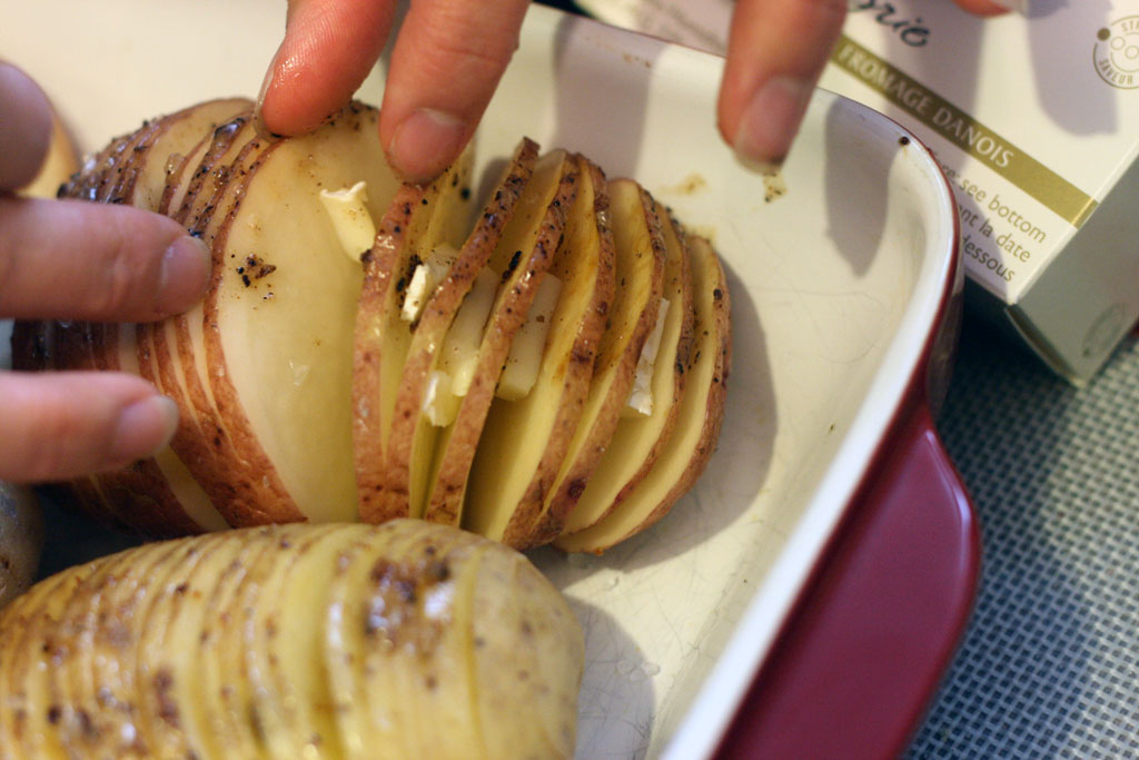 Each slice of the hasselback potatoes have cheese stuffed inside. From above: hasselback potatoes sliced and stuffed with brie cheese.