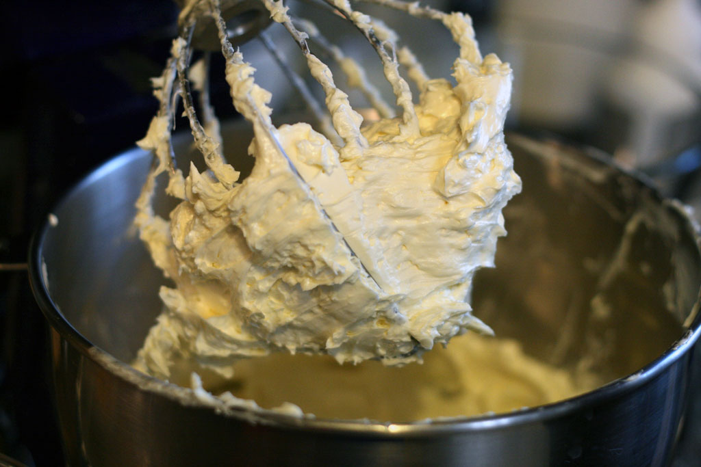 A whisk attachment loaded with whipped buttercream