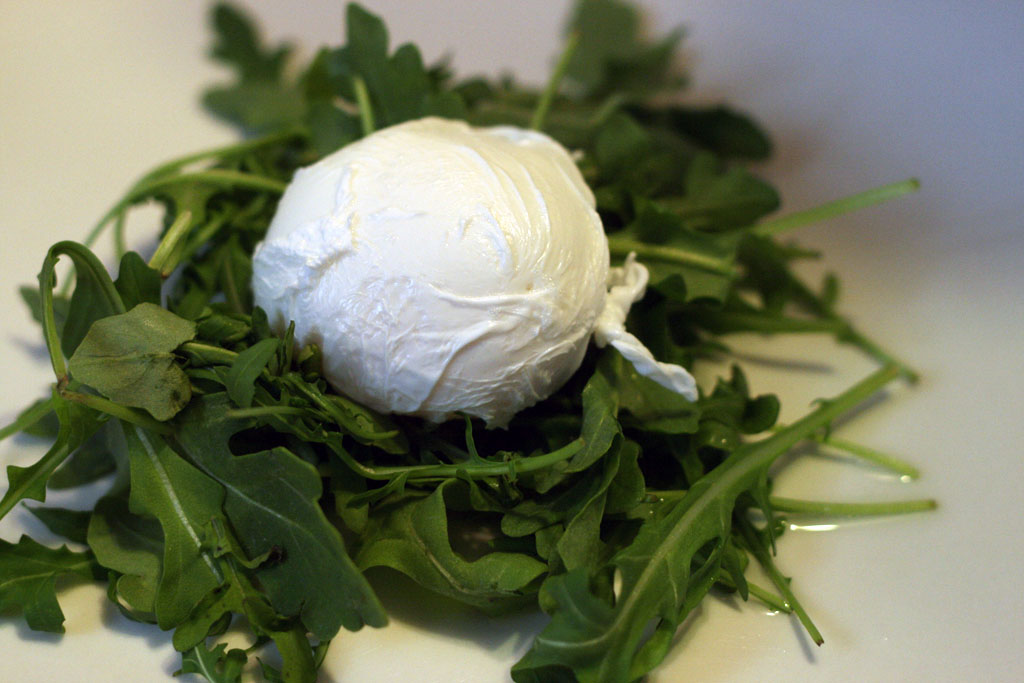 Finished poached egg on a bed of arugula leaves.