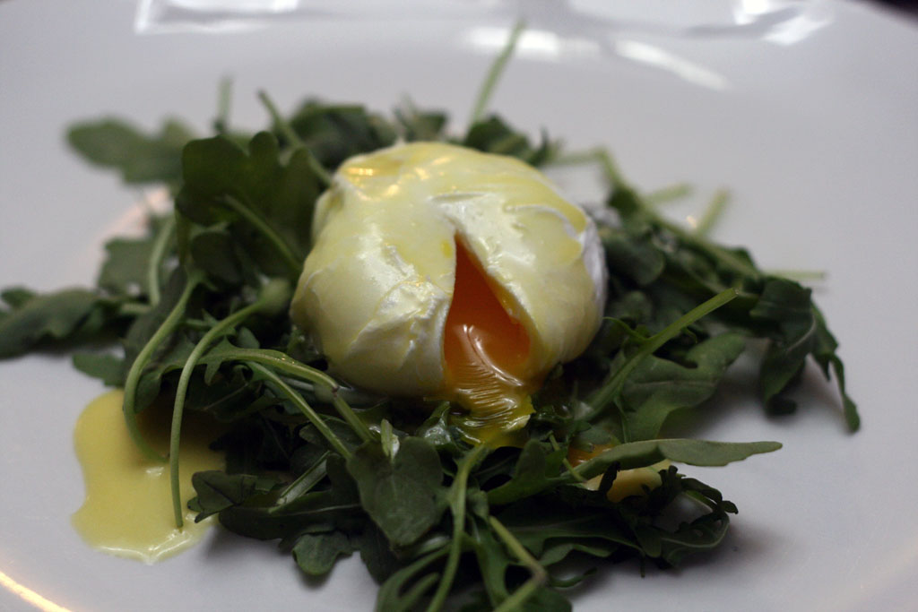 Soft poached eggs with homemade hollandaise sauce on a bed of arugula.