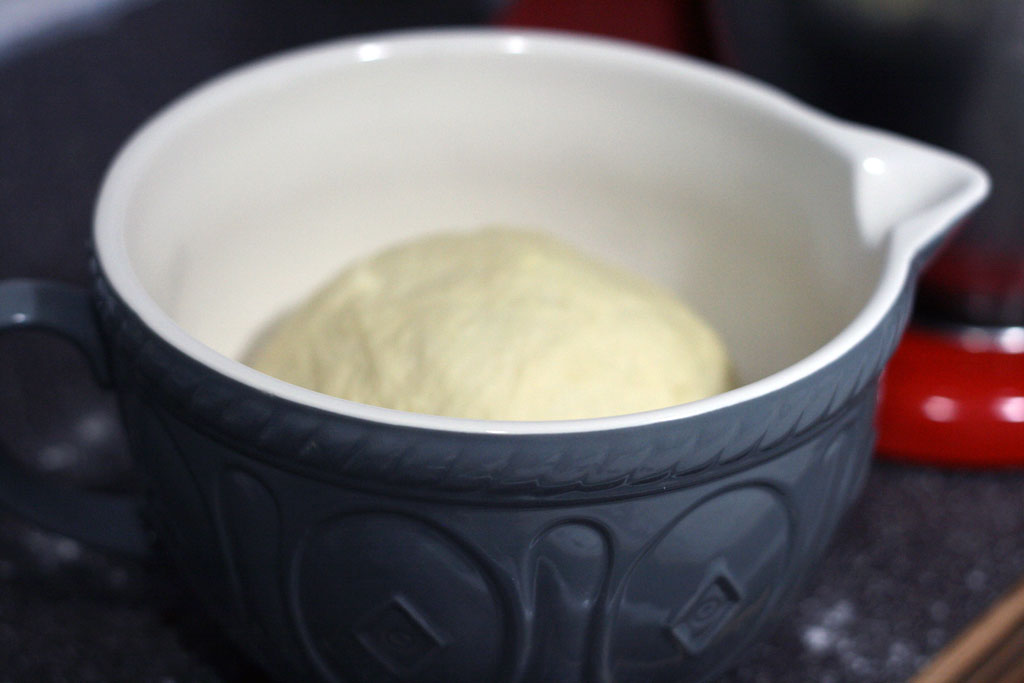 Dough sitting in an oiled mason cash bowl
