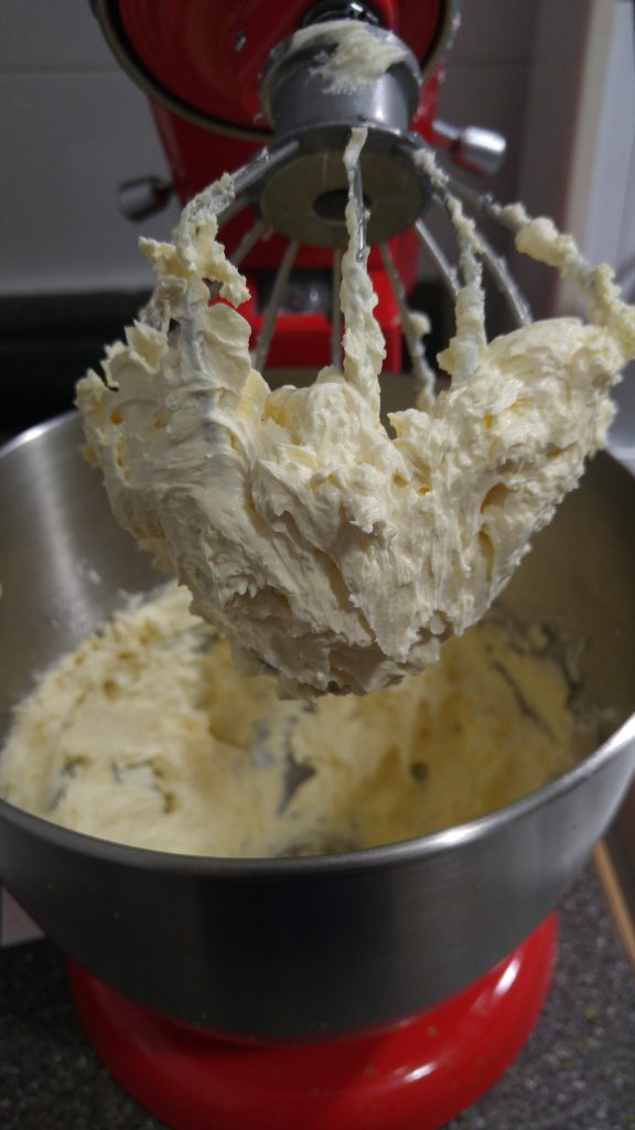 A whisk full of plain white buttercream, to be used for the matcha buttercream filling.