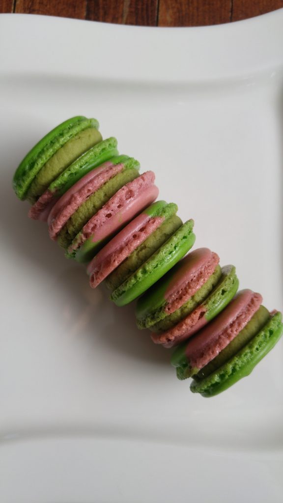 A plate of raspberry matcha macarons stacked sideways.