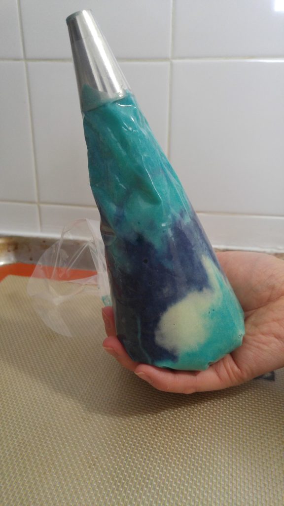 The dual coloured macaron batter in a piping bag.