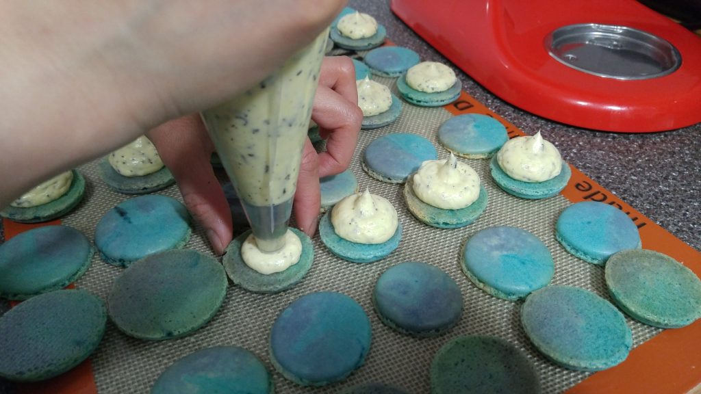 Piping the buttercream onto the cosmic macaron shells.