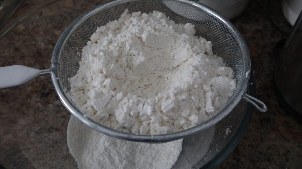 icing sugar in a sifter above a bowl