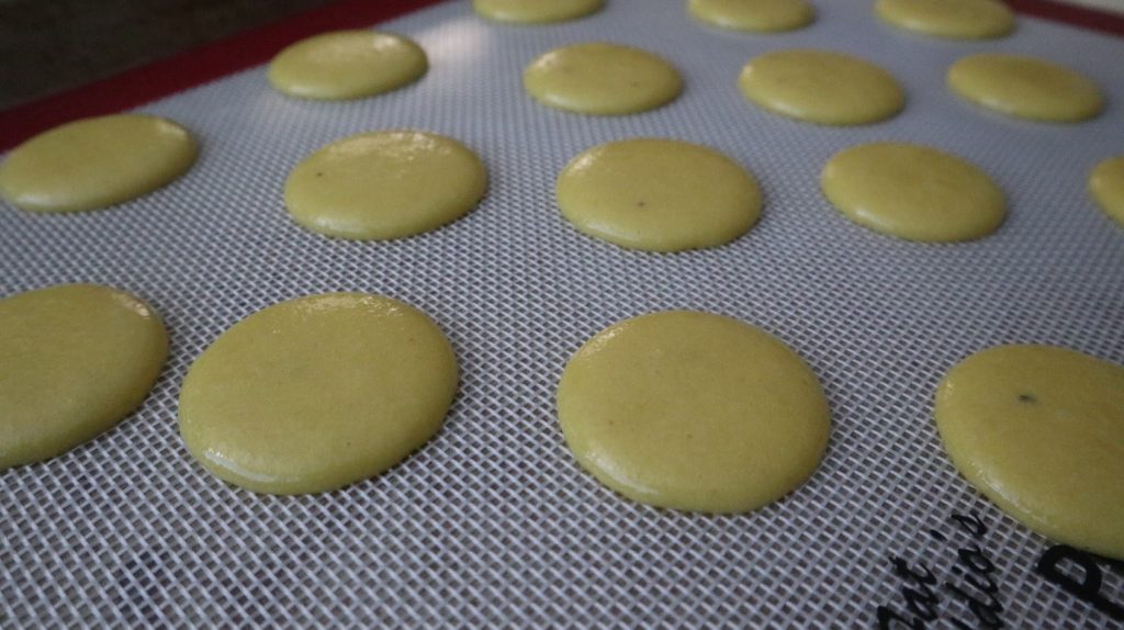 macaron shells piped and resting on a silicon mat