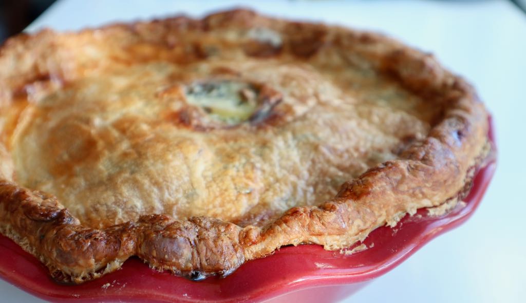 nice fluffy golden colour potato tourte inside a red deep pie dish