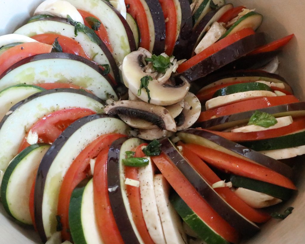 Alternating slices of eggplant, green zucchini, tomato, and mushroom.